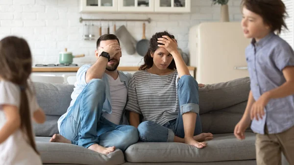 Tired young parents exhausted from loud kids playing — Stok fotoğraf