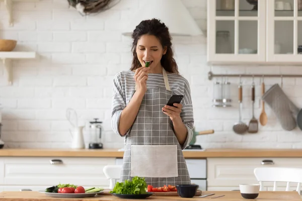 Lächelnde junge Frau kocht in Küche mit Zelle — Stockfoto
