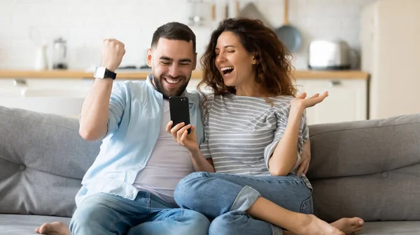 Emocionada joven pareja triunfa leyendo noticias en la celda —  Fotos de Stock