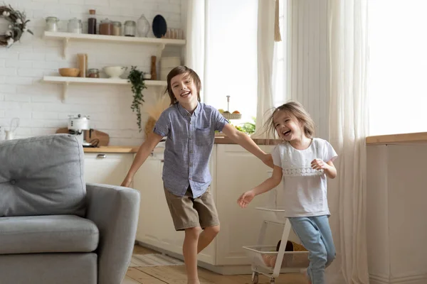 Irmãos alegres se divertem correndo em casa — Fotografia de Stock