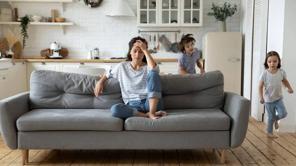 Exhausted young mother annoyed from loud children — Stockfoto