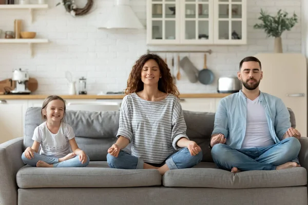 Küçük kızı olan genç bir aile birlikte yoga yapıyor.