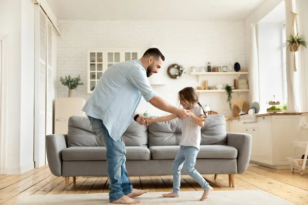 Счастливый молодой отец танцует был милый дошкольник дочь в доме — стоковое фото