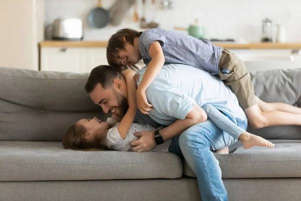 Счастливый отец играет с двумя маленькими детьми дома — стоковое фото