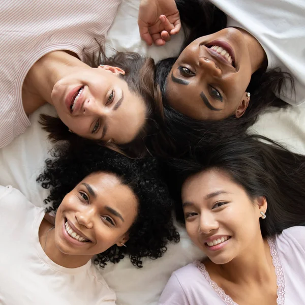 Top view różnorodne młode kobiety przyjaciele leżące w łóżku razem — Zdjęcie stockowe