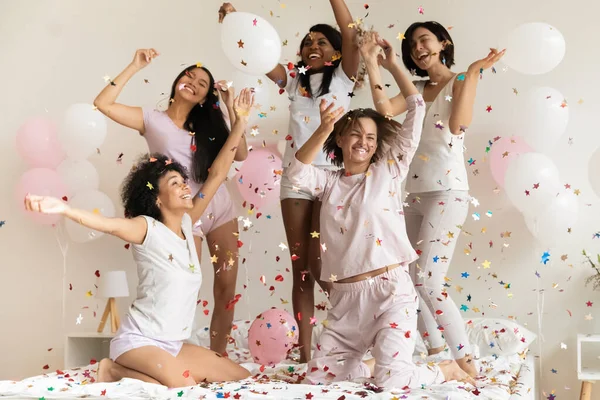Счастливые разнообразные девушки в пижамах бросают конфетти, веселятся — стоковое фото