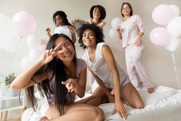 Portrait funny beautiful girls dancing on bed at sleepover party — Stockfoto