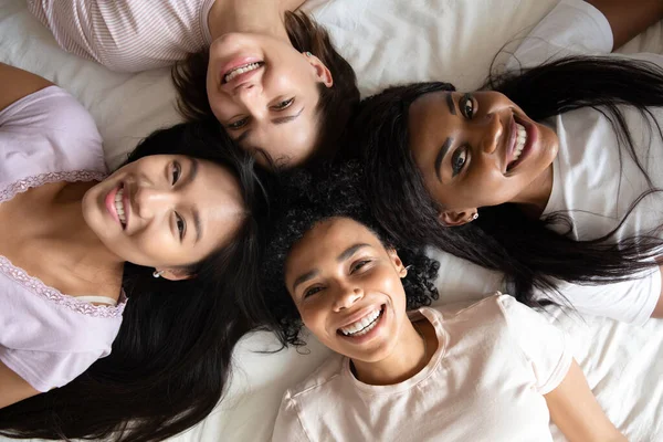 Top view mulheres diversas melhores amigos deitados na cama juntos — Fotografia de Stock