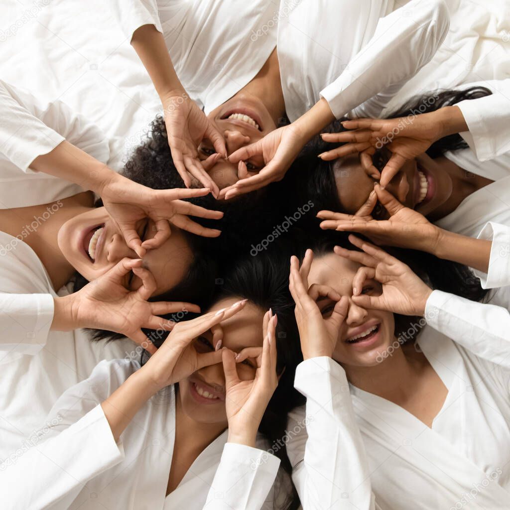 Top view funny diverse girls making binoculars, looking at camera