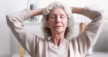 Sakin gülümseyen yaşlı 70 yaşındaki kadın evde dinleniyor.