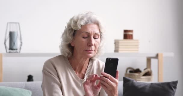 A boldog idős hölgy jó híreket olvas a mobil győzelem koncepciójáról. — Stock videók