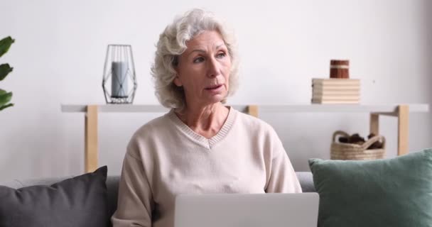 Счастливая пожилая женщина использует ноутбук, глядя на экран — стоковое видео