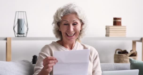 Cheerful old woman reads mail letter excited by good news — Stock Video