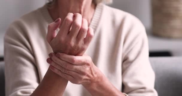 Senior Großmutter massiert Hand, die an rheumatoider Arthritis leidet — Stockvideo