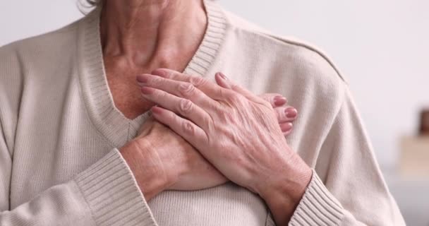 Agradecida anciana complacida cogida de la mano en el pecho, primer plano — Vídeo de stock