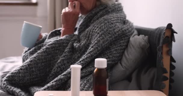 Older ill woman blowing nose in bed near cold remedy — Stock Video