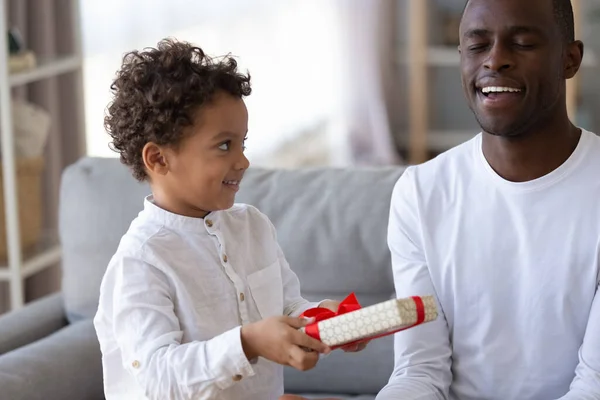 Lilla son gör överraskningsgåva för leende afroamerikansk far — Stockfoto