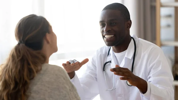Leende afroamerikansk läkare konsulterar kvinnlig patient på mötet — Stockfoto