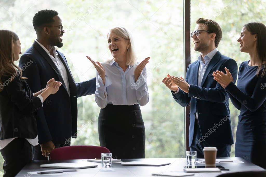 Overjoyed diverse employees celebrate team business success together