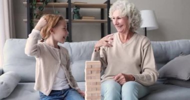 Mutlu büyük anneler ve torunlar evde Jenga oynuyorlar.