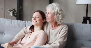 Happy serene grandmother and grown granddaughter bonding at home