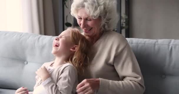 Glückliche Senior-Großmutter kitzelt süße kleine Enkelin zu Hause — Stockvideo