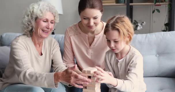 Семья из нескольких поколений играет в настольную игру Дженга — стоковое видео