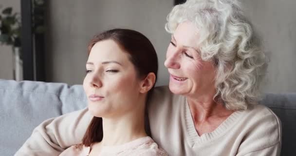 Relaxed senior mother embracing young daughter and talking on sofa — Αρχείο Βίντεο