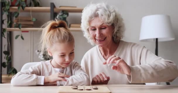 Happy two age generations family playing draughts game at table — Stockvideo