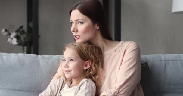Soñadora madre soltera abraza linda hija hablando relajante en el sofá — Vídeo de stock