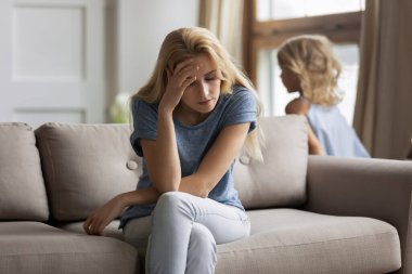 Yorgun anne kanepede oturup baş ağrısı çekiyor.