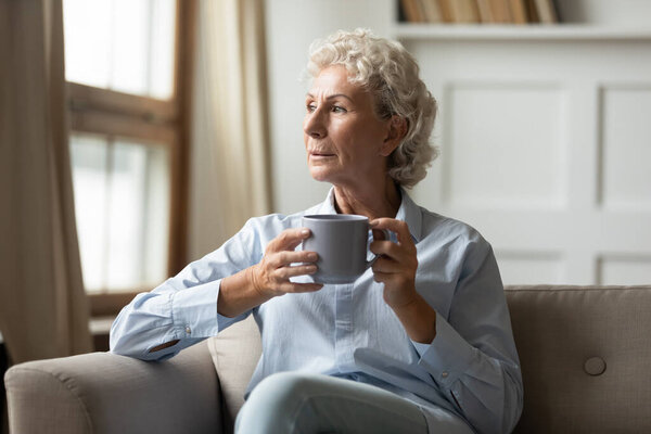 Pensive mature woman look in distance dreaming or thinking