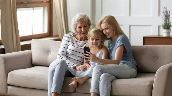 Três gerações de mulheres usam o celular juntas — Fotografia de Stock