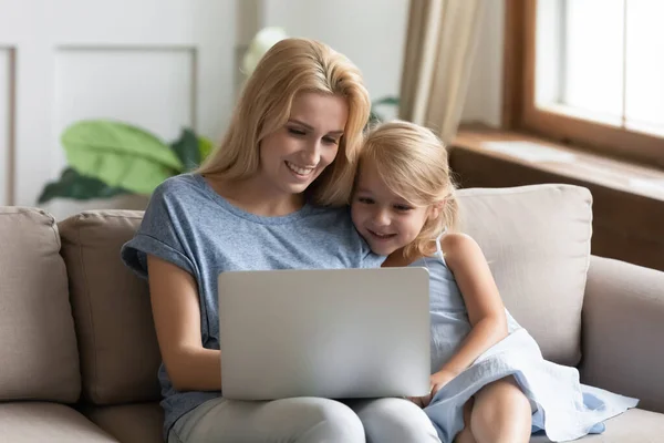 Young mom watch video on laptop with little daughter