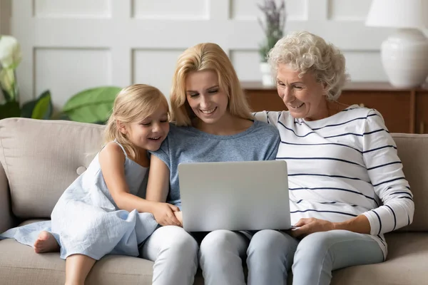 Three generations of women watch video on laptop