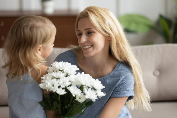 Schattig klein meisje gefeliciteerd jong mam presenteren bloemen — Stockfoto