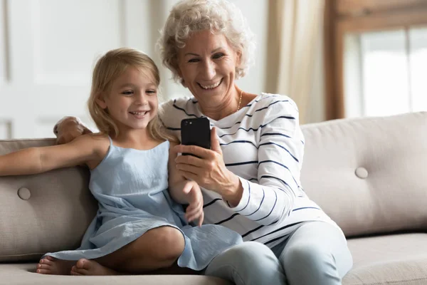 Avó feliz e neto pequeno usando celular em casa — Fotografia de Stock