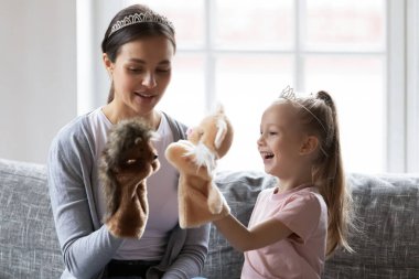 Taç takan mutlu küçük kız bebek bakıcısıyla el oyuncakları oynuyor..