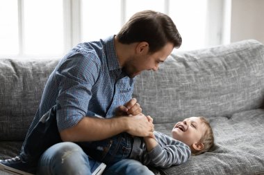 Mutlu genç baba küçük gülen çocuğu gıdıklıyor.