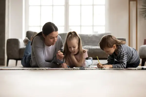 Jonge oppas babysitter tekening foto met kleine kinderen. — Stockfoto