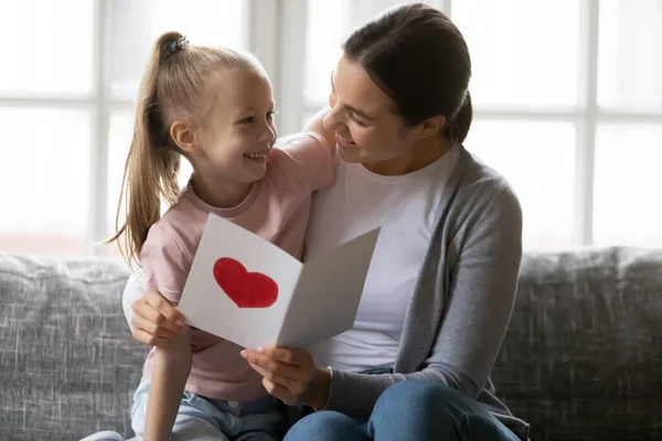 Прихильна любляча мати обіймає маленьку доньку, читаючи привітання в листі . — стокове фото