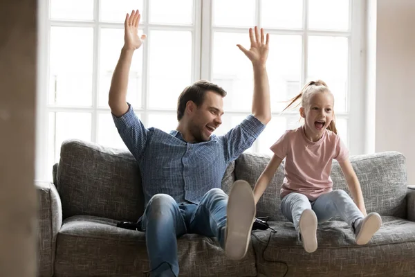 Eccitato giovane padre che celebra la vittoria del videogioco con la figlia felicissima . — Foto Stock