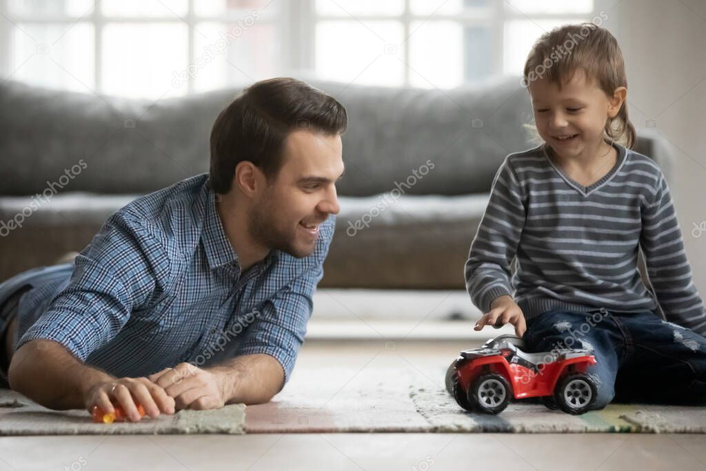 Joyful young father playing car toys with son.