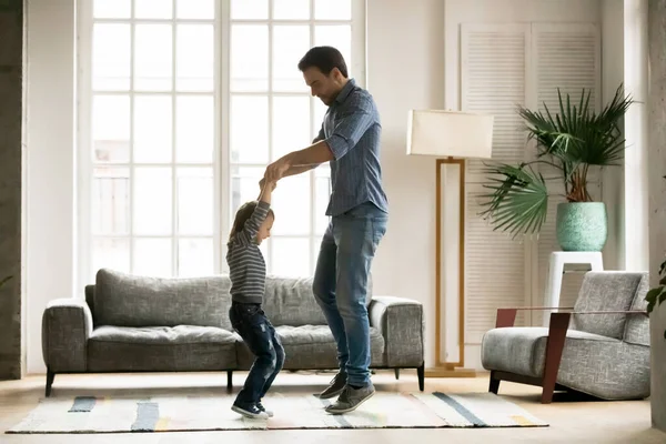 Dolblij kleine peuter jongen springen met vader thuis. — Stockfoto