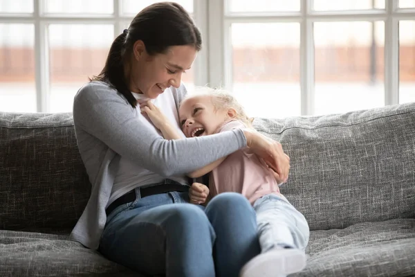 Happy young mother tickling little blonde daughter. — Stock Photo, Image
