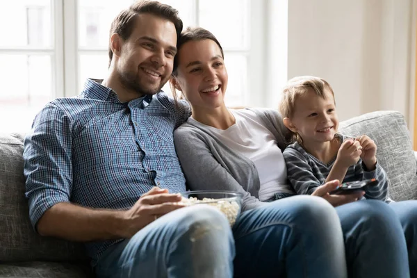 Joyful family couple cuddling son, watching tv show. — Stock Photo, Image