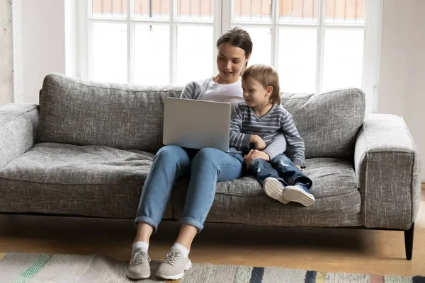 Mujer joven viendo películas divertidas en la computadora con hijo niño . — Foto de Stock