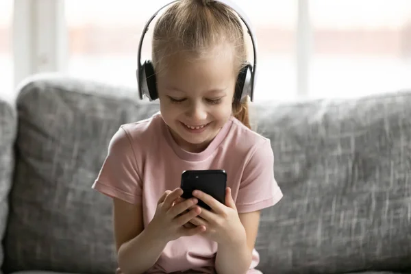 Petite fille heureuse portant des écouteurs sans fil, écouter de la musique . — Photo