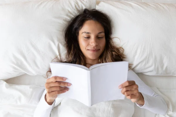 Mujer joven descanso en cama acogedora lectura libro en casa — Foto de Stock