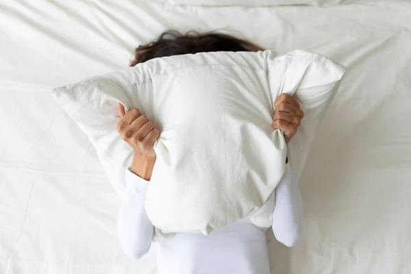 Woman cover face with pillow suffering from depression